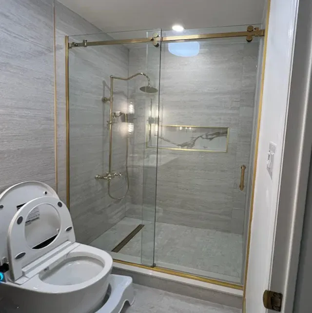 Sliding glass shower door with brass track and hardware