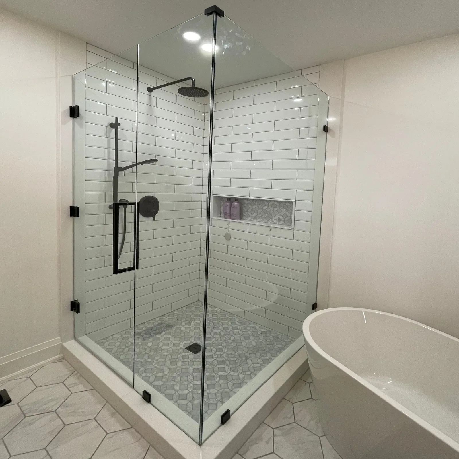 Frameless corner shower with black hinges and white subway tile