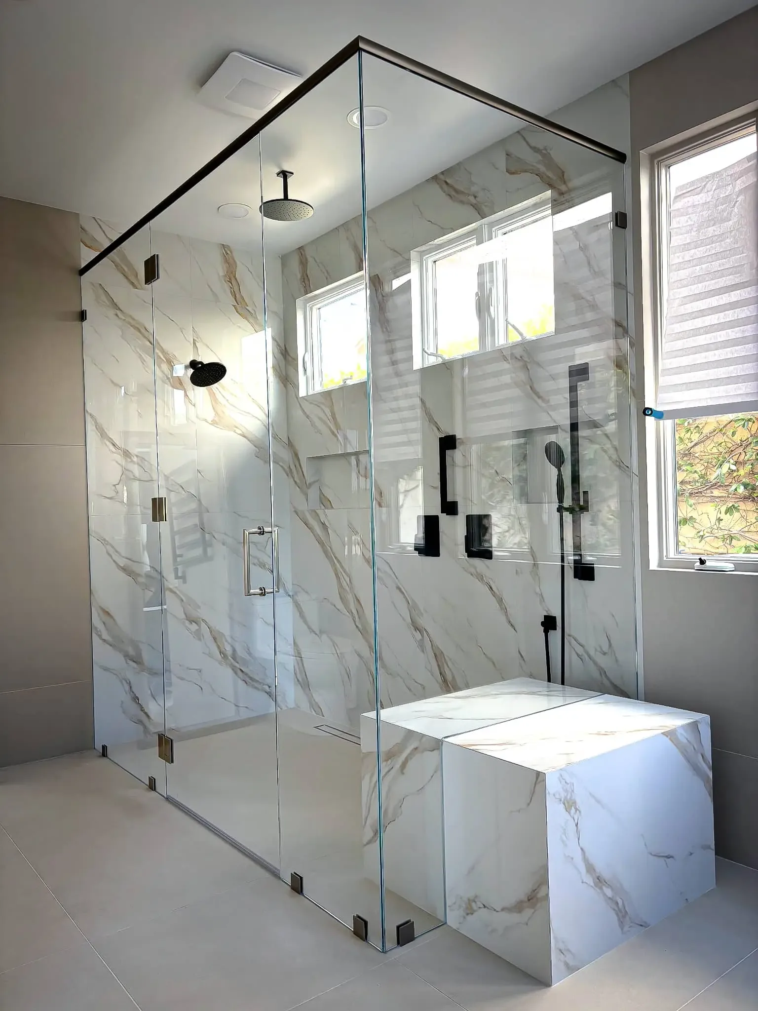 Frameless glass shower enclosure with marble tile