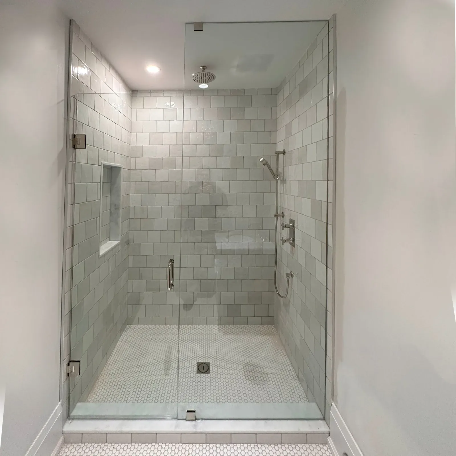 Frameless hinged glass door on a tiled walk-in shower